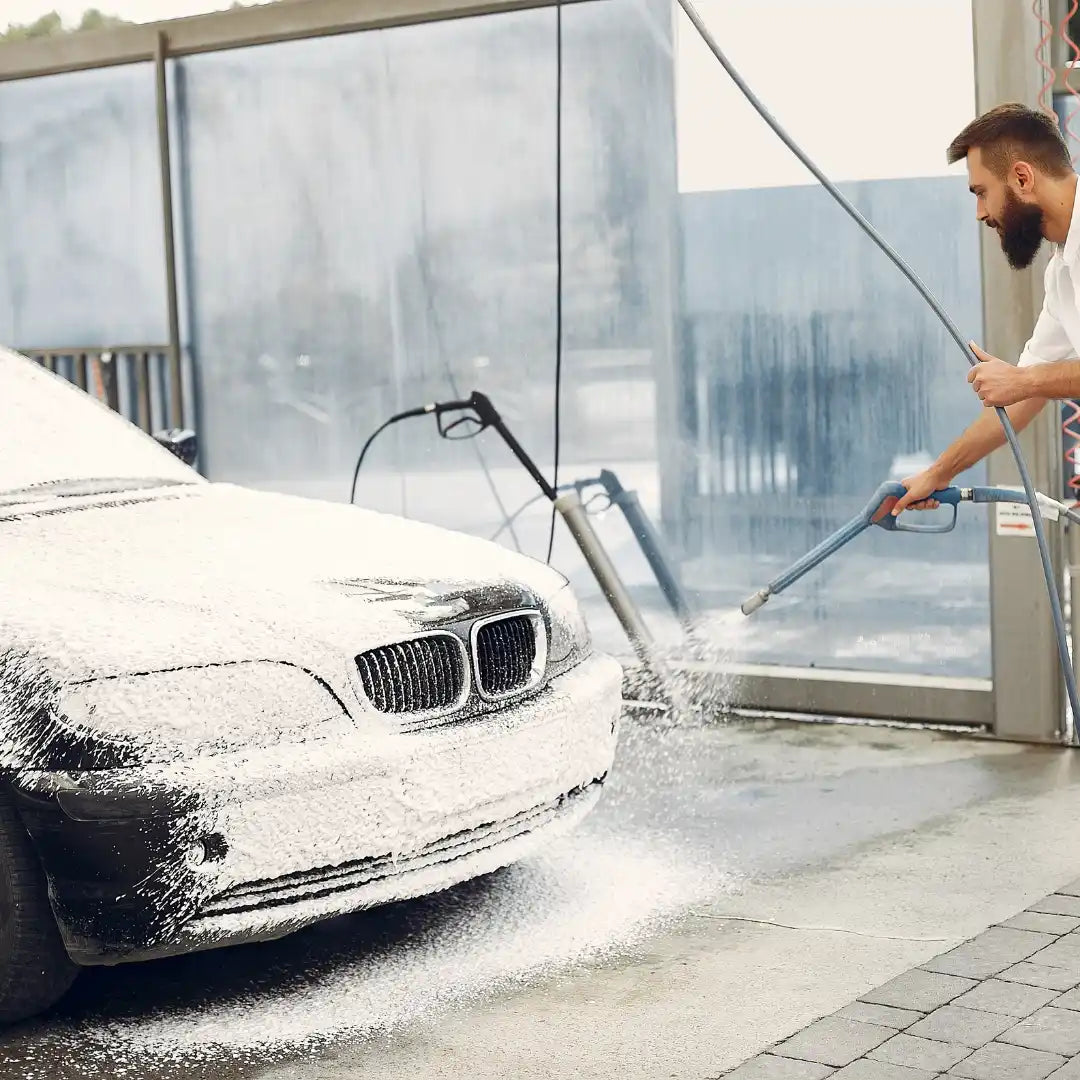 Mașina BMW acoperită de spumă fiind spălată cu un aparat de spălat sub presiune.