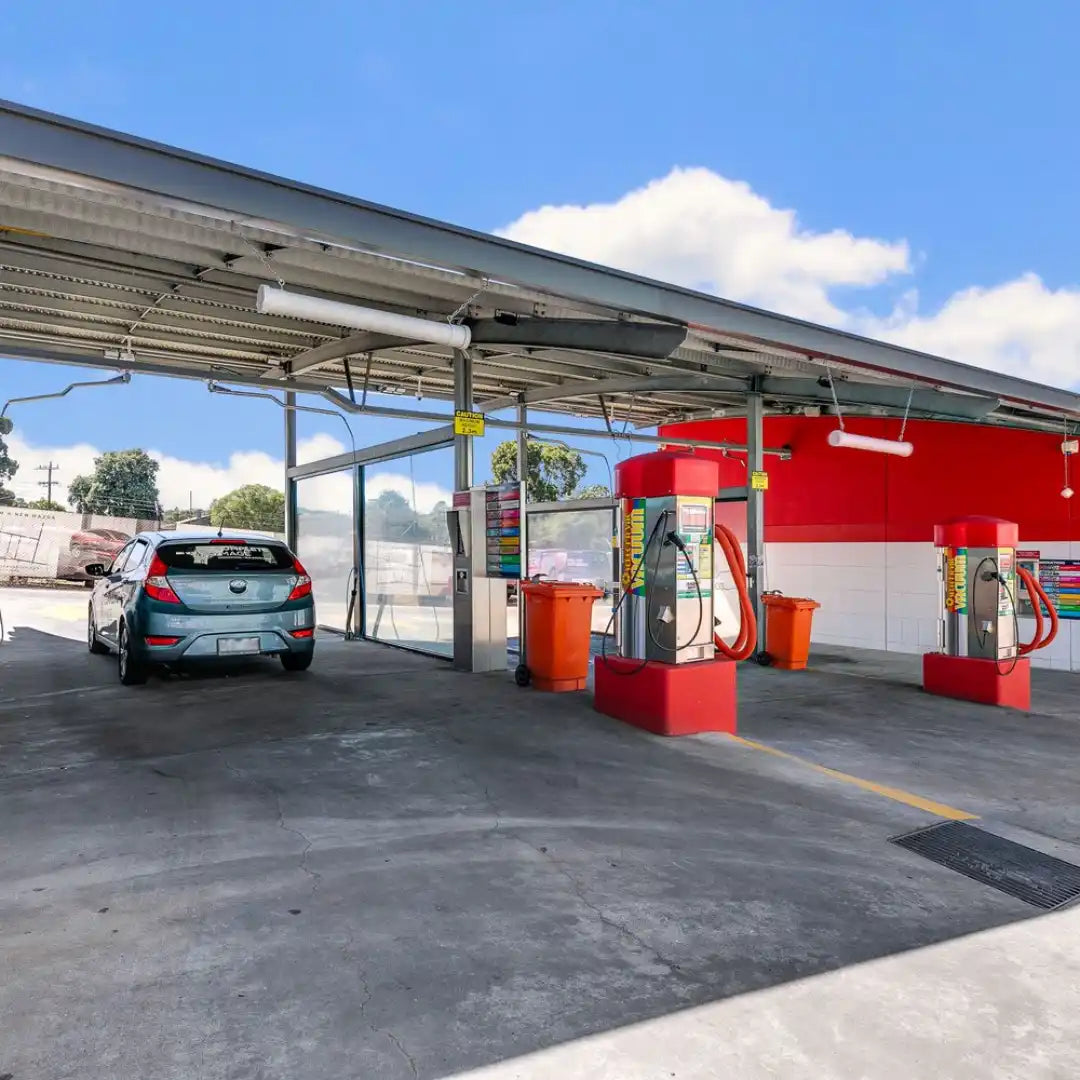 Stație de combustibil cu pompe de carburant sub o zonă acoperită.